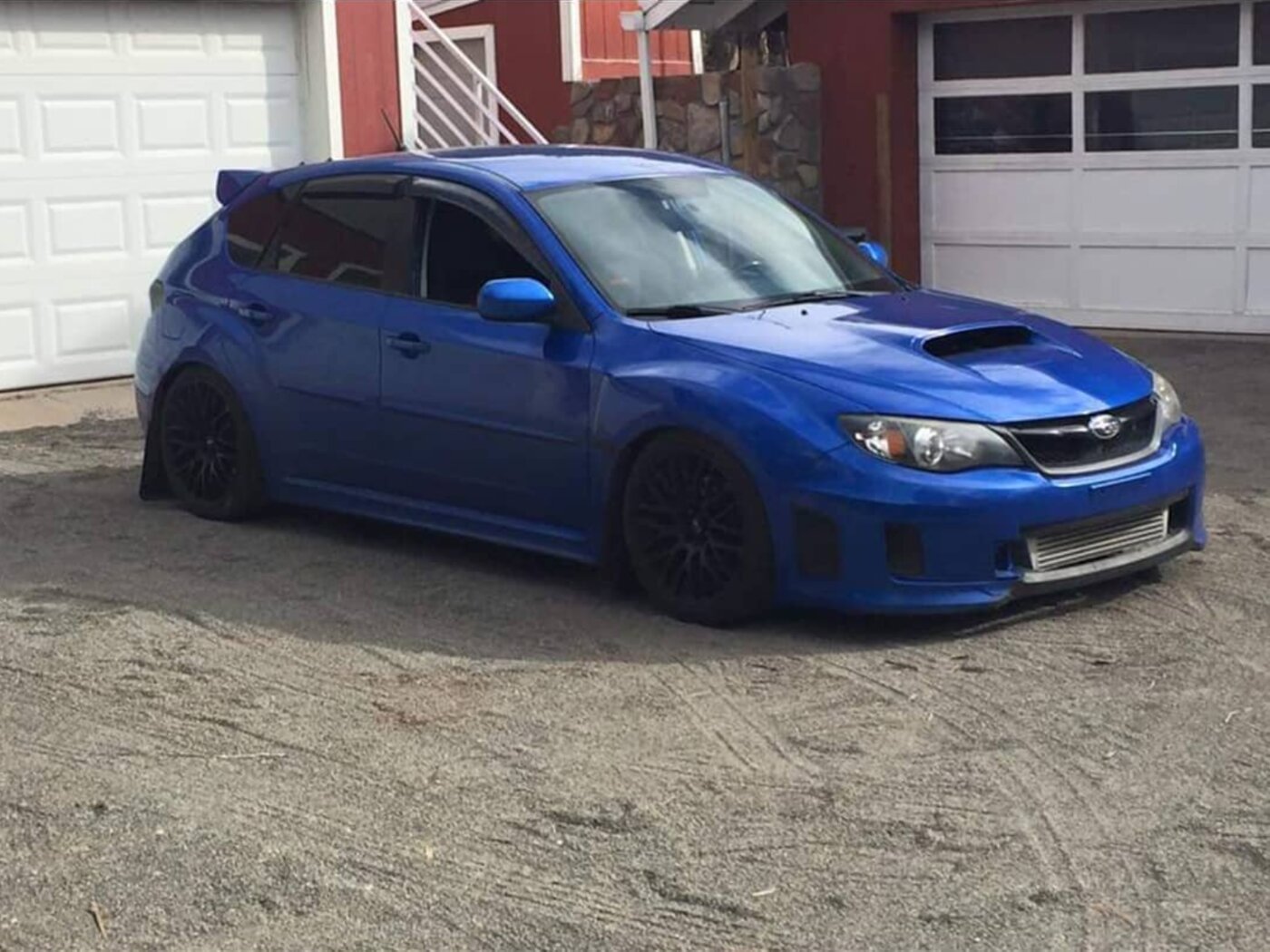 A blue Subaru WRX STI hatchback fitted with a lowered suspension